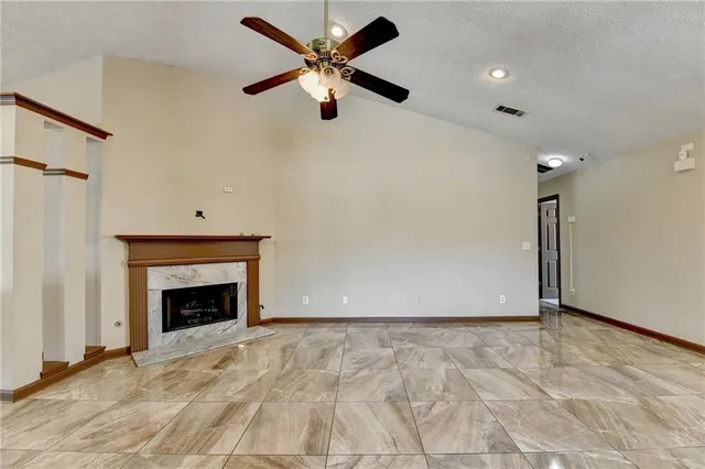 an empty room with ceiling fan and a fireplace