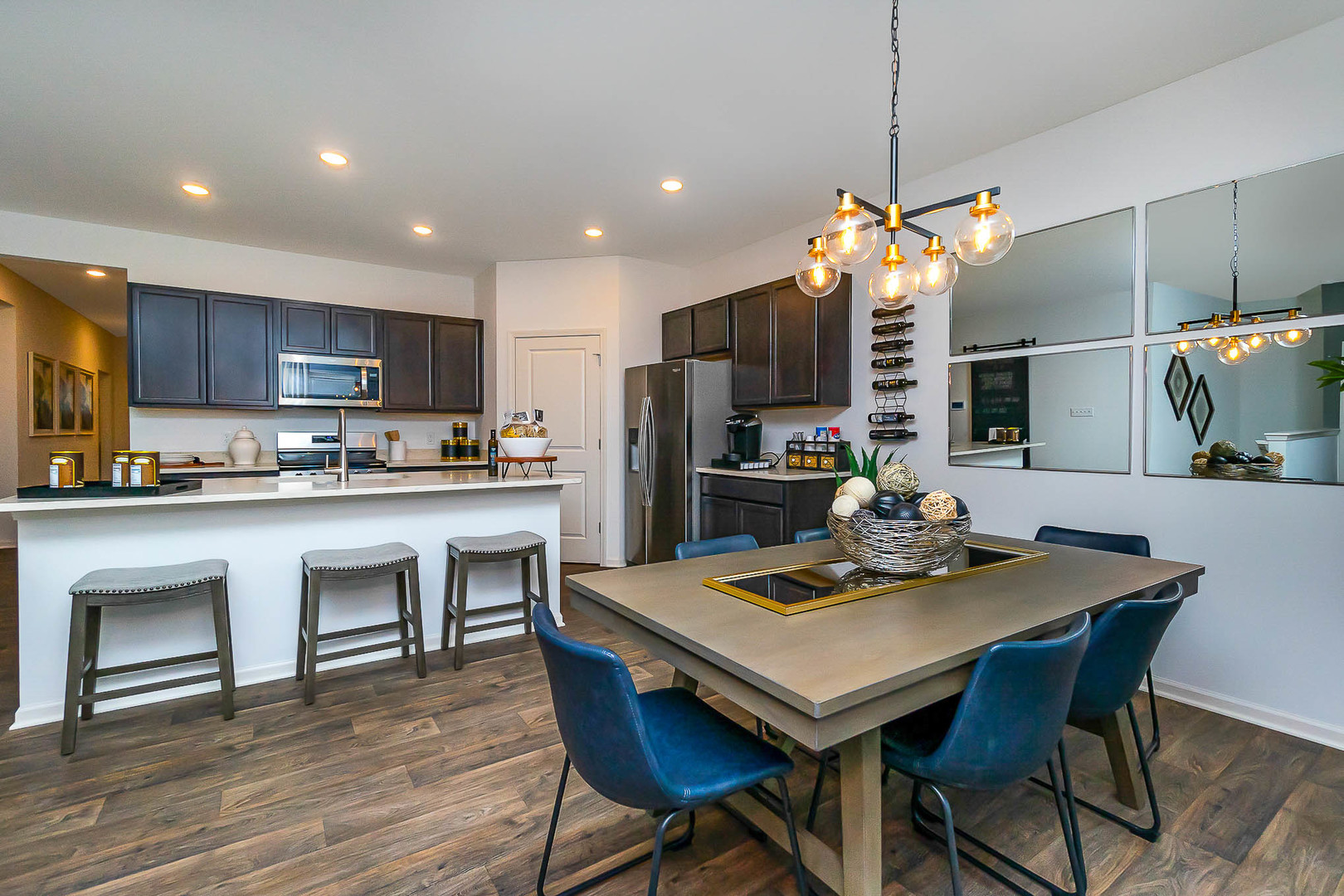 7600 West 105th Place Crown Point, IN 46307 - Photo 16 of 34 a kitchen with stainless steel appliances granite countertop a stove a refrigerator a microwave a dining table and chairs with wooden floor