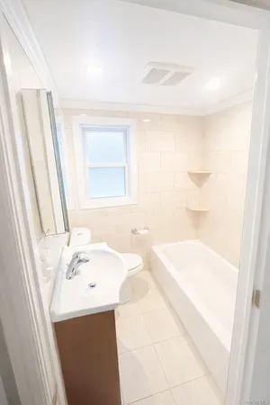 a bathroom with a bathtub a sink and a window