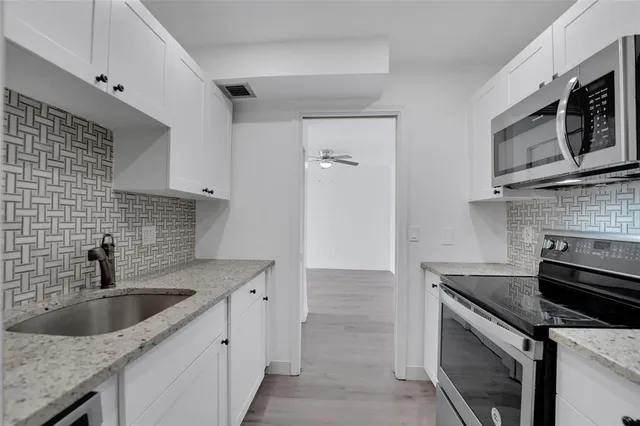a kitchen with stainless steel appliances granite countertop a sink stove and microwave