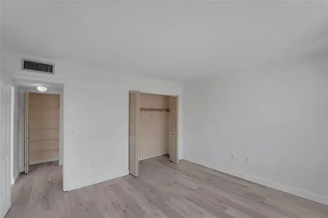 an empty room with wooden floor and closet