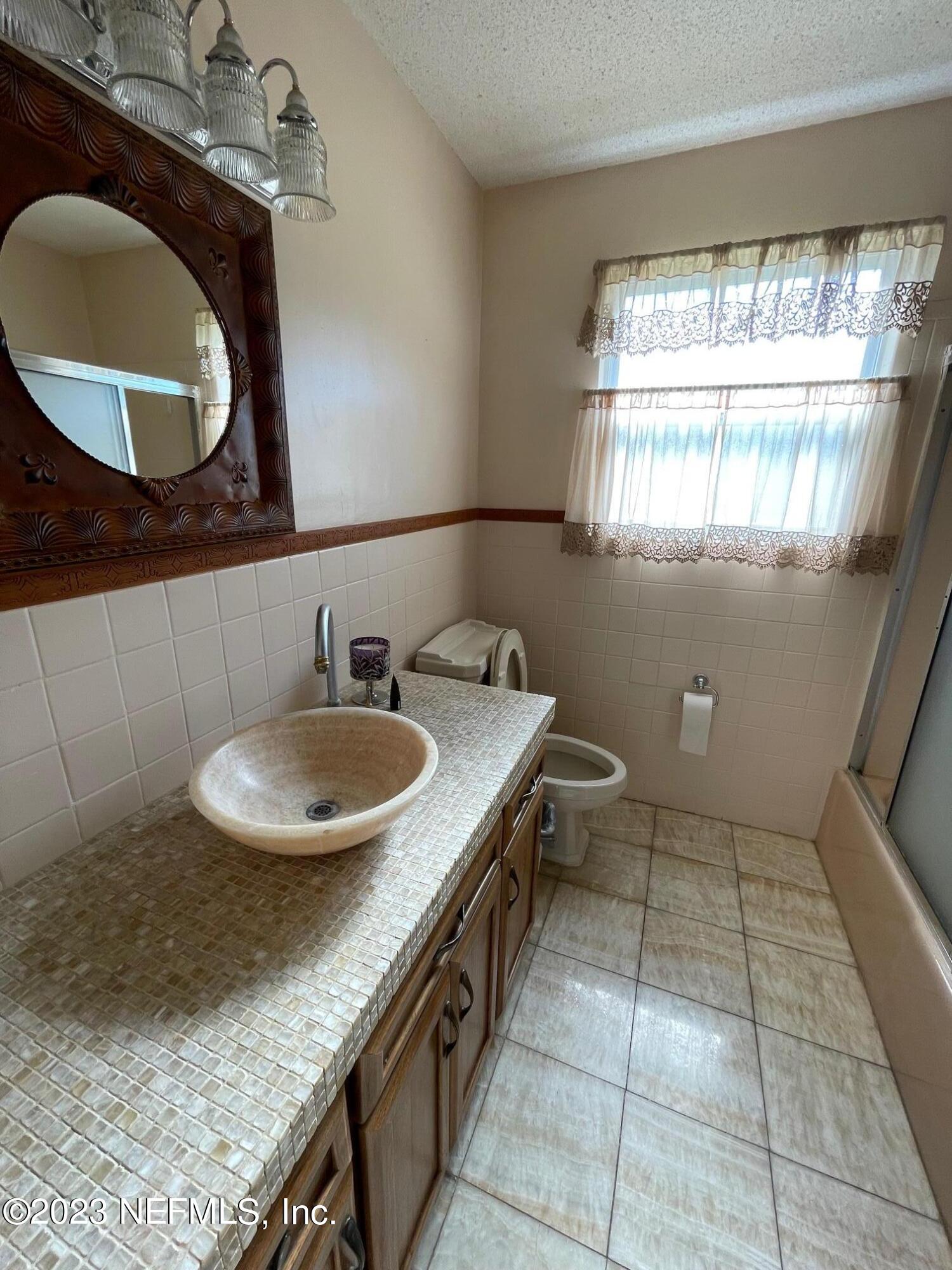 1042 Jamaica Road East Jacksonville, FL 32216 - Photo 21 of 59 a bathroom with a granite countertop sink a mirror and a window