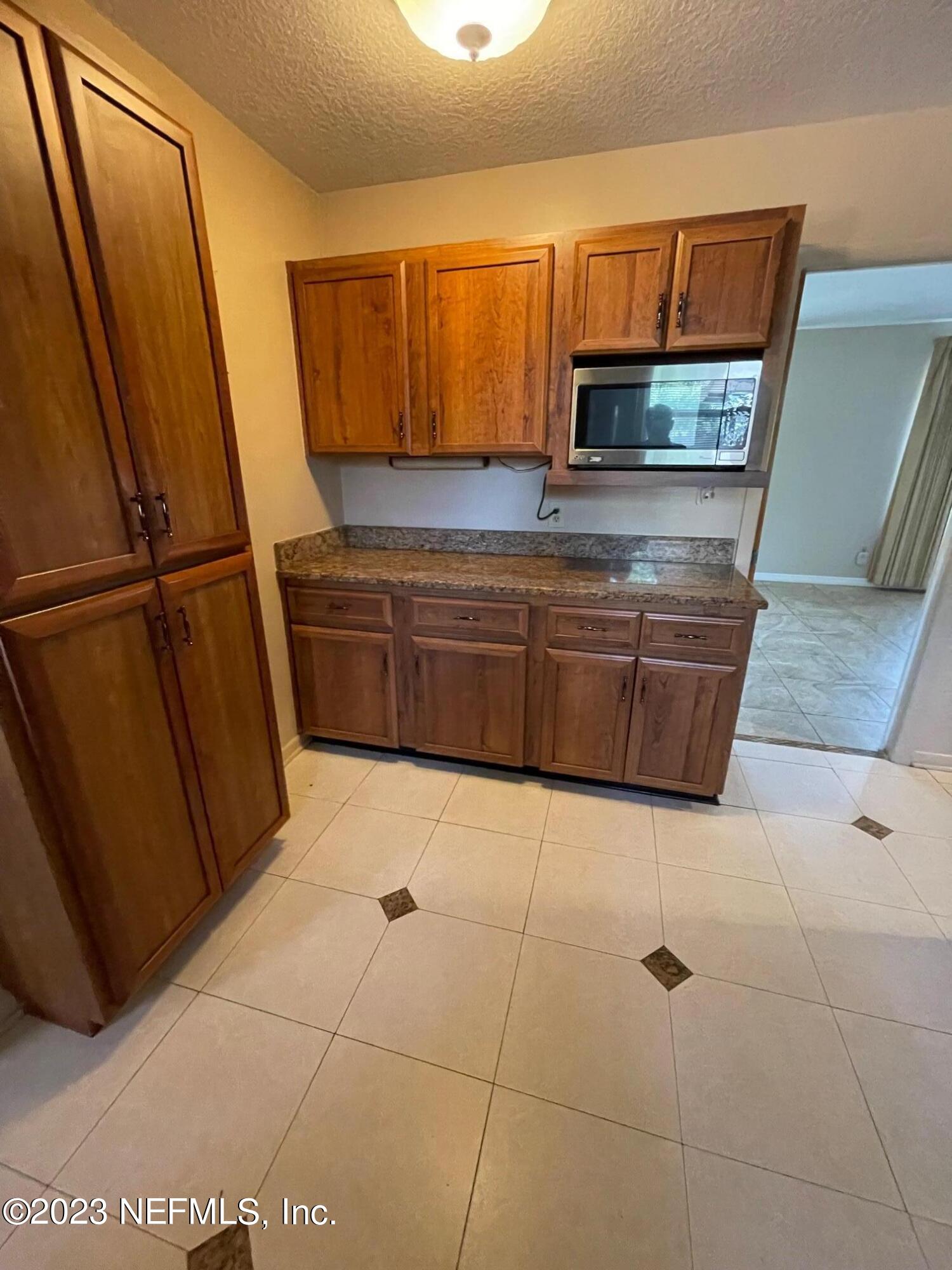 1042 Jamaica Road East Jacksonville, FL 32216 - Photo 29 of 59 a kitchen with granite countertop a refrigerator and a stove top oven