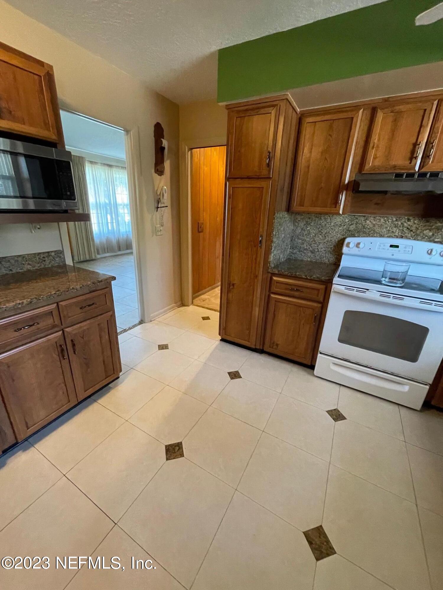 1042 Jamaica Road East Jacksonville, FL 32216 - Photo 30 of 59 a kitchen with granite countertop a stove a sink and a microwave