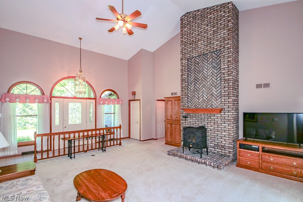 6475 Taylor Road Painesville, OH 44077 - Photo 4 of 23 Living room featuring a floor-to-ceiling brick fireplace with a wood-burning stove insert, vaulted ceiling, and a ceiling fan