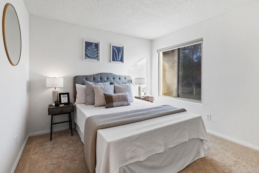 5918 Rancho Mission Road, Unit 62 San Diego, CA 92108 - Photo 18 of 37 a bedroom with a bed and a painting on the wall