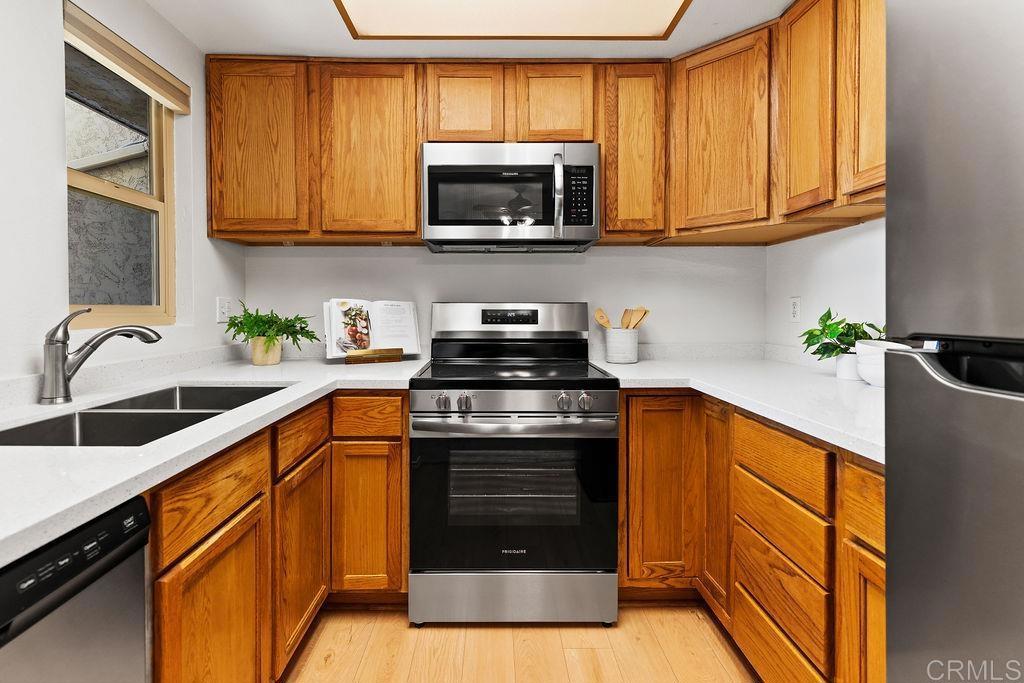 5918 Rancho Mission Road, Unit 62 San Diego, CA 92108 - Photo 4 of 37 a kitchen with granite countertop a stove a sink and a microwave