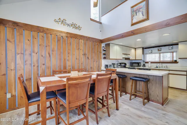 a kitchen with stainless steel appliances kitchen island granite countertop a table chairs sink and cabinets