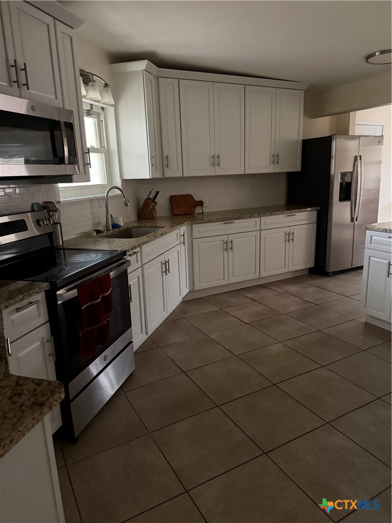 202 Bonham Street Port Lavaca, TX 77979 - Photo 3 of 11 a kitchen with stainless steel appliances granite countertop a stove a sink and a refrigerator