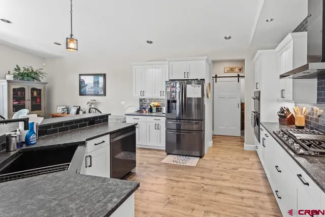 a kitchen with stainless steel appliances granite countertop a stove refrigerator and a sink