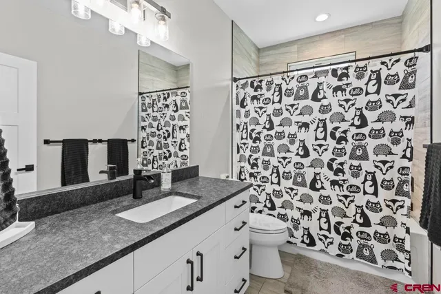 a bathroom with a granite countertop sink a toilet and a shower