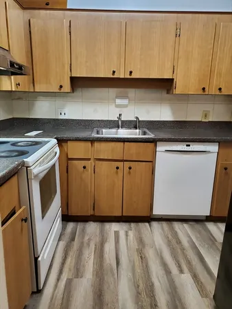 a kitchen with stainless steel appliances granite countertop a stove a sink and a white cabinet