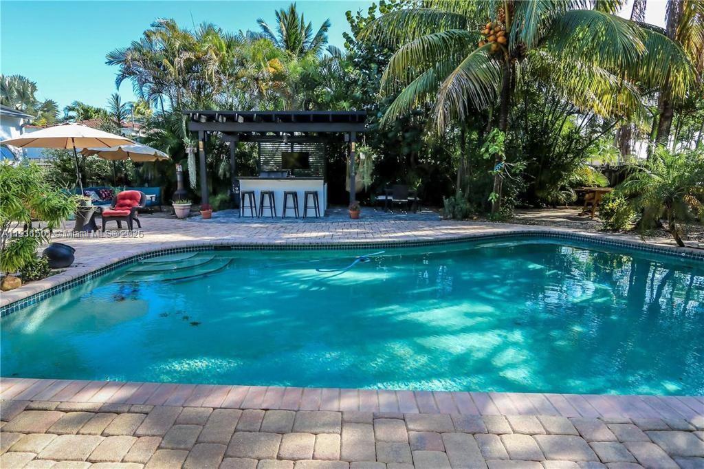 1516 Funston Street Hollywood, FL 33020 - Photo 4 of 23 a view of a patio with table and chairs under an umbrella with large trees