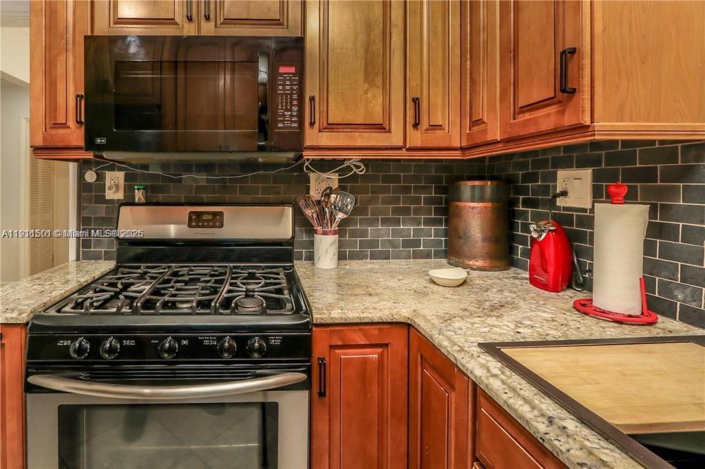 1516 Funston Street Hollywood, FL 33020 - Photo 9 of 23 a kitchen with granite countertop a stove and cabinets