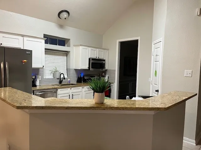 a kitchen with kitchen island granite countertop a sink and a refrigerator
