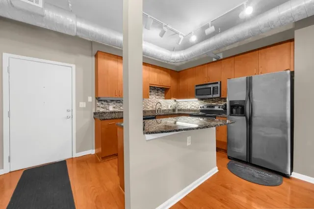 a kitchen with stainless steel appliances granite countertop a refrigerator a stove and a sink