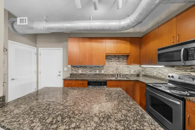 a kitchen with stainless steel appliances granite countertop a sink and a stove