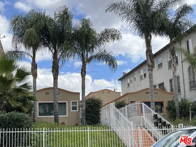a front view of a house with balcony and palm trees