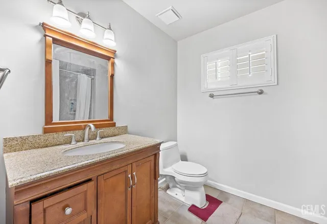 a bathroom with a granite countertop sink a toilet and a mirror