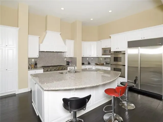 a kitchen with stainless steel appliances granite countertop a sink a stove a refrigerator and a dining table