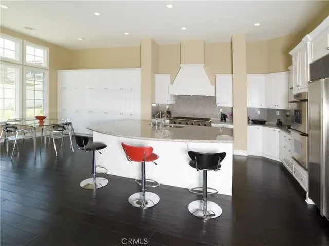 a kitchen with stainless steel appliances kitchen island granite countertop a stove a refrigerator a oven a sink with a dining table and chairs