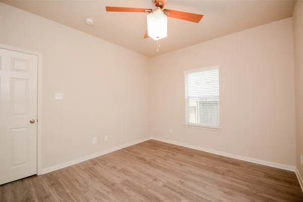 an empty room with windows and fan