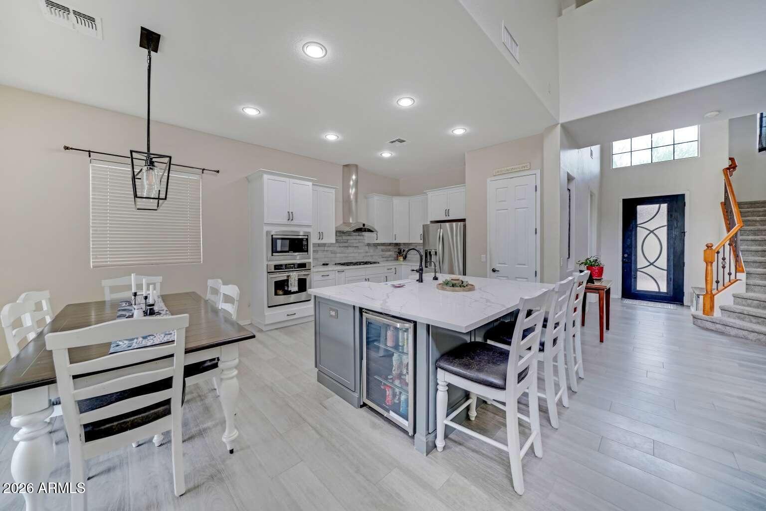 3978 East Hashknife Road Phoenix, AZ 85050 - Photo 8 of 29 a kitchen with kitchen island a dining table chairs sink and white cabinets