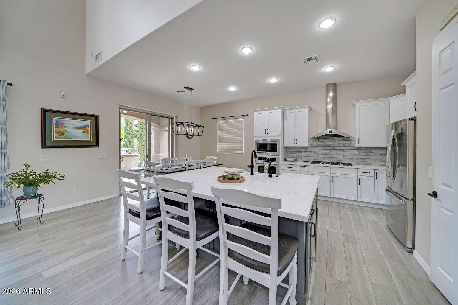 3978 East Hashknife Road Phoenix, AZ 85050 - Photo 9 of 29 a kitchen with stainless steel appliances kitchen island granite countertop a refrigerator a stove a sink a dining table and chairs with wooden floor