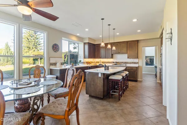 a kitchen with stainless steel appliances kitchen island granite countertop a table chairs and a refrigerator
