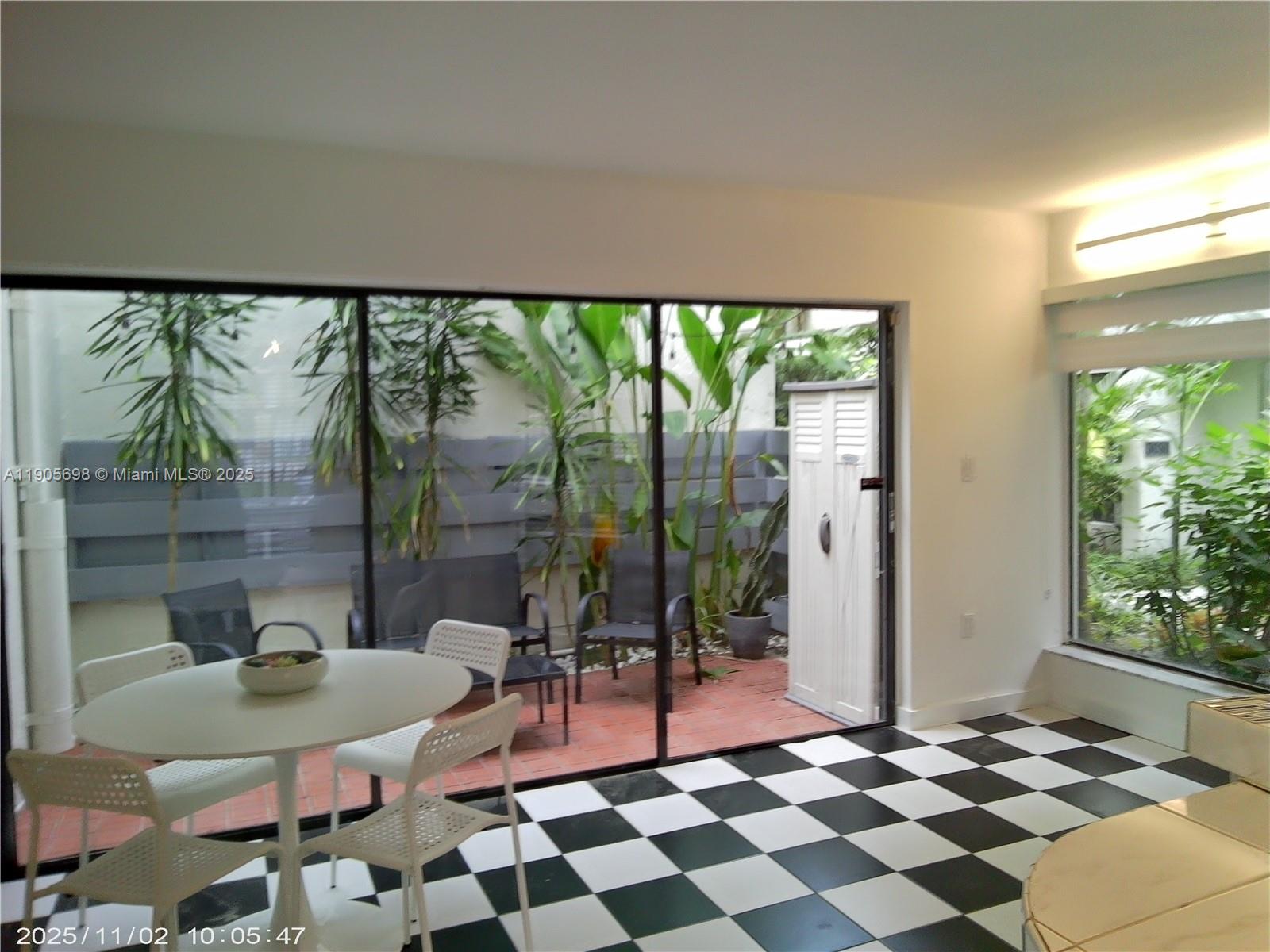 3036 Southwest 27th Avenue, Unit 5 Miami, FL 33133 - Photo 3 of 23 a living room with a black white checkered floor with a gaming machine and dining table