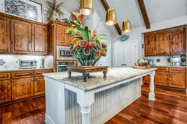 a kitchen with stainless steel appliances granite countertop a sink and cabinets with wooden floor