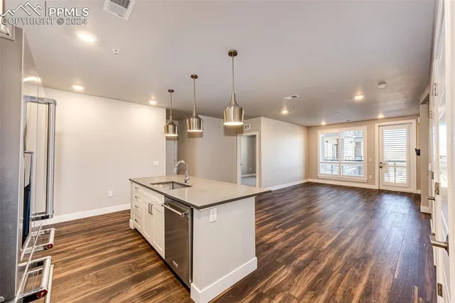 a hall with kitchen island white cabinets and wooden floor