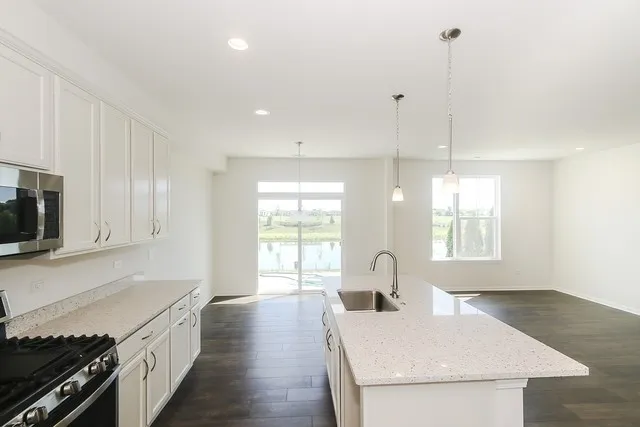 a large kitchen with stainless steel appliances granite countertop a sink a stove a microwave a counter space and cabinets