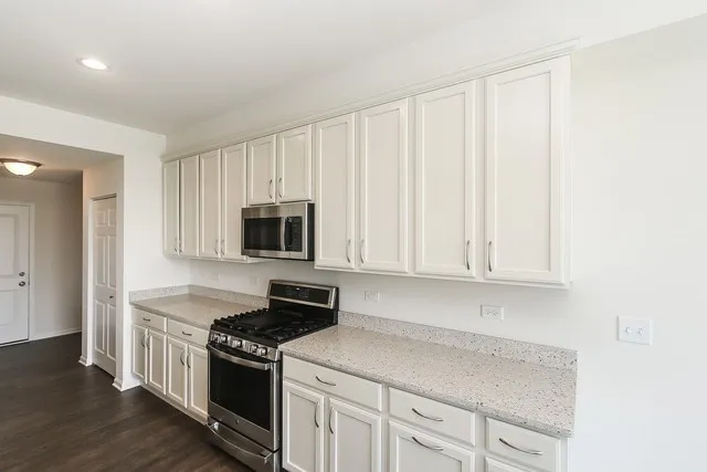 a kitchen with granite countertop white cabinets and stainless steel appliances