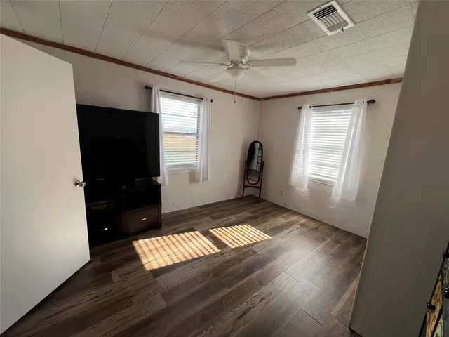 a view of an empty room with a window and wooden floor
