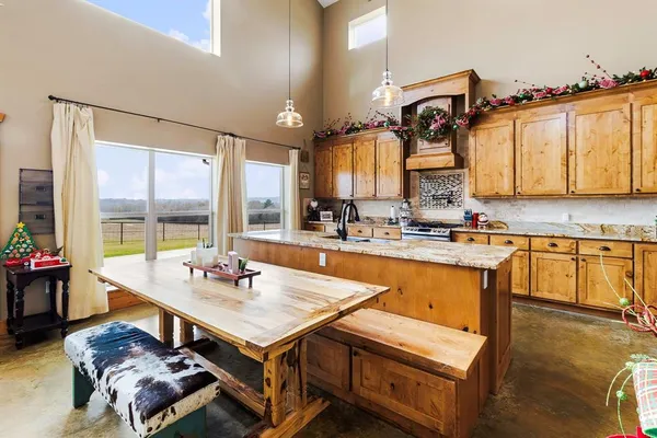 a living room with stainless steel appliances granite countertop a table chairs and a sink