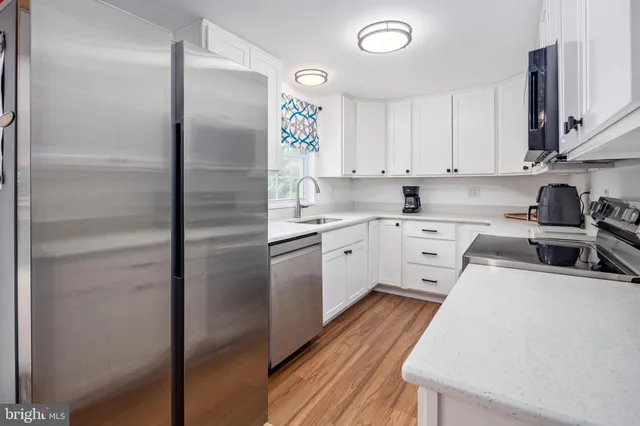 a kitchen with a sink stainless steel appliances and white cabinets