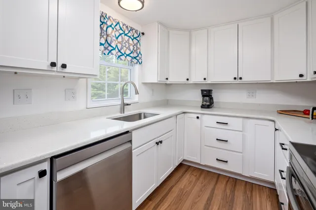 a kitchen with granite countertop white cabinets and white appliances with wooden floor