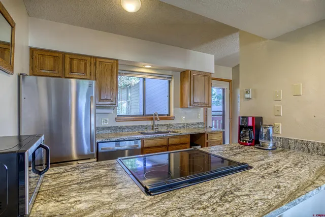 a kitchen with kitchen island granite countertop a sink and a refrigerator