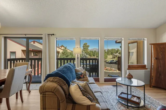 a living room with furniture a large window and wooden floor