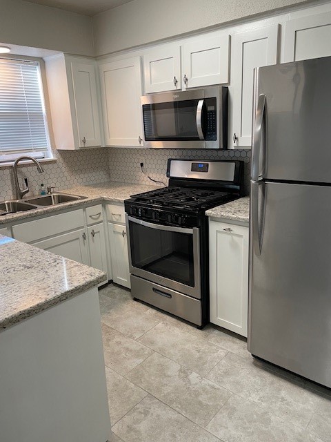407 West Semands Street Conroe, TX 77301 - Photo 14 of 28 a kitchen with granite countertop a sink stove and refrigerator