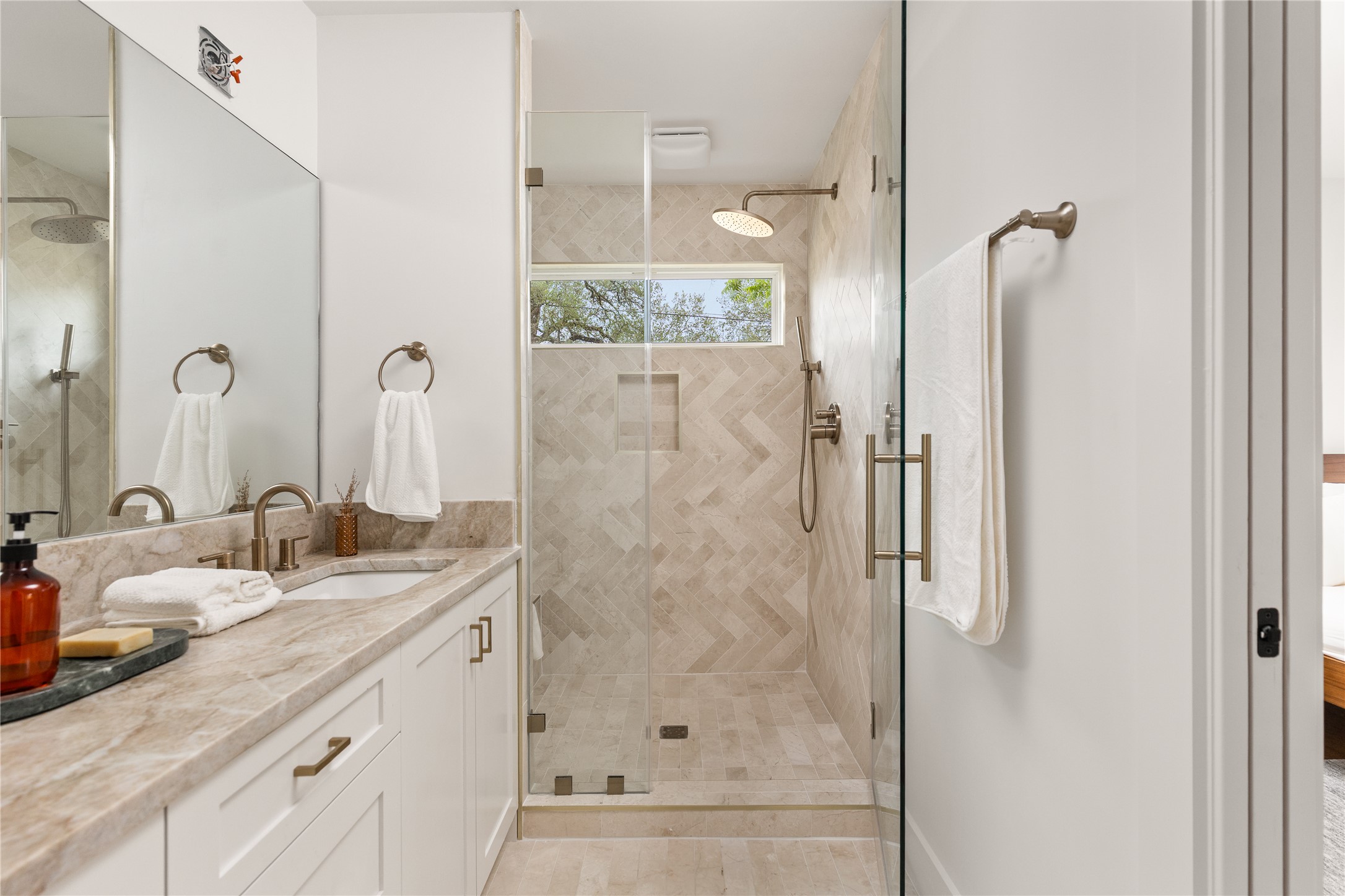 4501 Pack Saddle Pass Austin, TX 78745 - Photo 26 of 37 Bathroom featuring a frameless glass-enclosed shower with herringbone tile, a rain shower head, and a transom window