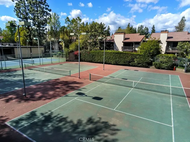 a view of a tennis ground with large trees