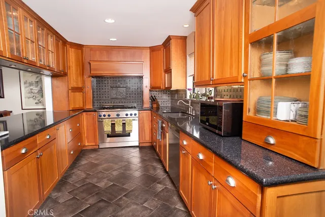 a large kitchen with stainless steel appliances a large counter top a stove a sink and a refrigerator