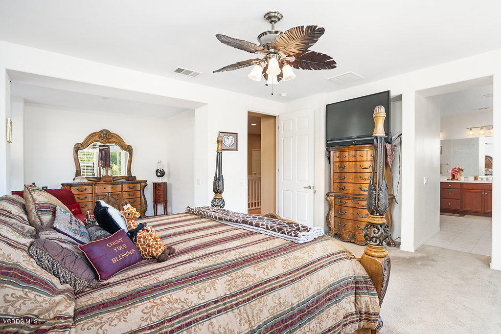 13709 Swift Run Street Moorpark, CA 93021 - Photo 18 of 34 a bedroom with a large bed a chandelier and dresser