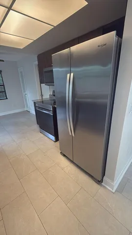 a view of a refrigerator in kitchen and an empty room