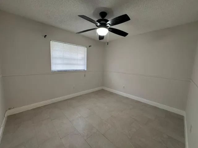 en empty room with ceiling fan and window
