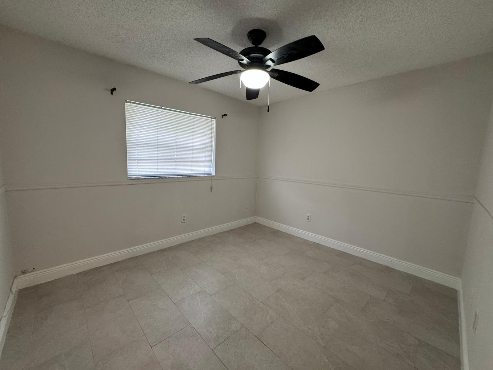 9244 Southwest 2nd Street Boca Raton, FL 33428 - Photo 7 of 11 en empty room with ceiling fan and window