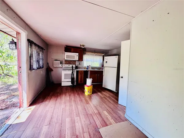 a living room with stainless steel appliances furniture a refrigerator and wooden floor