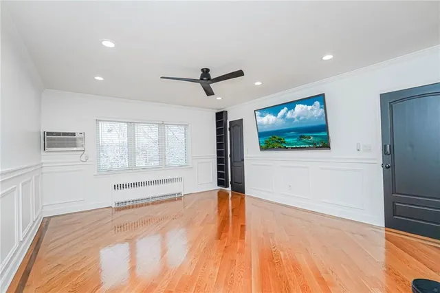 a view of an empty room with window and wooden floor